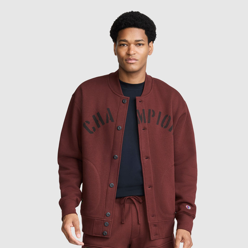 A person wears a maroon Champion Fleece Baseball Jacket with black lettering across the chest.