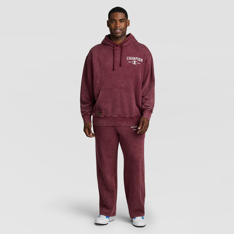 A man wearing a burgundy Mineral Wash Pullover Hoodie, C Patch Logo and matching sweatpants.