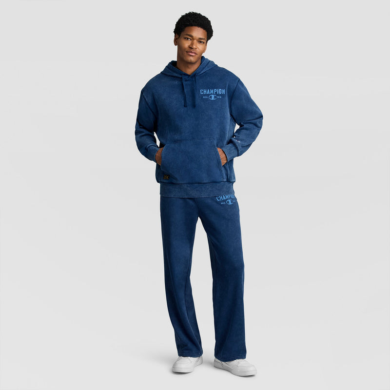 A person wearing a blue mineral wash Mineral Wash Pullover Hoodie, C Patch Logo and matching sweatpants, both featuring blue logo text on the chest and thigh.