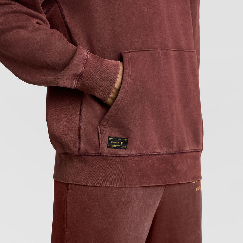 A dark red Mineral Wash Pullover Hoodie, C Patch Logo by Champion, featuring a kangaroo pocket and a small rectangular label near the hem.