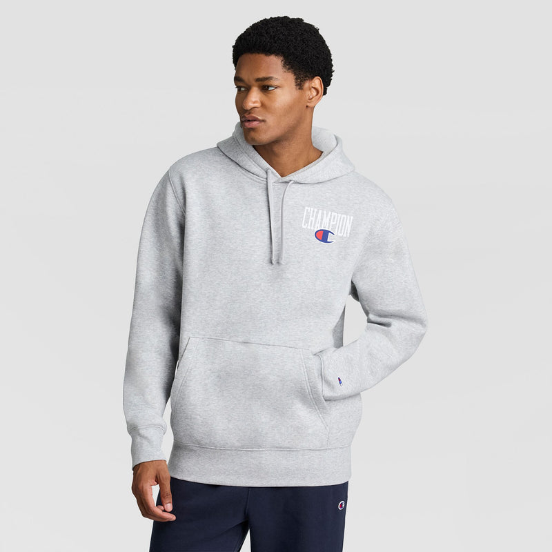 A person wearing a grey Champion Fleece Hoodie, Left Chest Graphic, with a logo on the left chest.