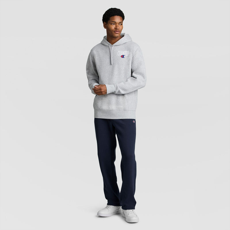 A person wearing a grey Fleece Hoodie, Left Chest Graphic, dark blue sweatpants, and white sneakers.