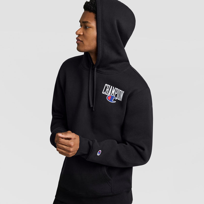 A person wearing a black Champion Fleece Hoodie, Left Chest Graphic, with a logo on the left chest and a small patch on the sleeve.