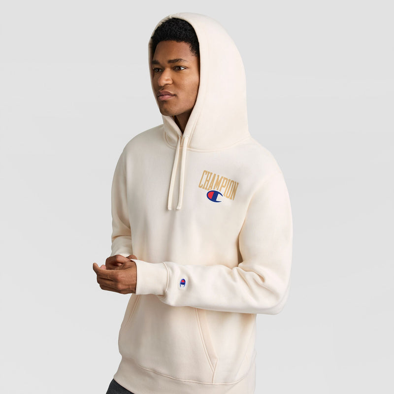 A man wearing an off-white Fleece Hoodie, Left Chest Graphic in lightweight cotton-poly fleece with a gold and blue Champion logo on the chest.