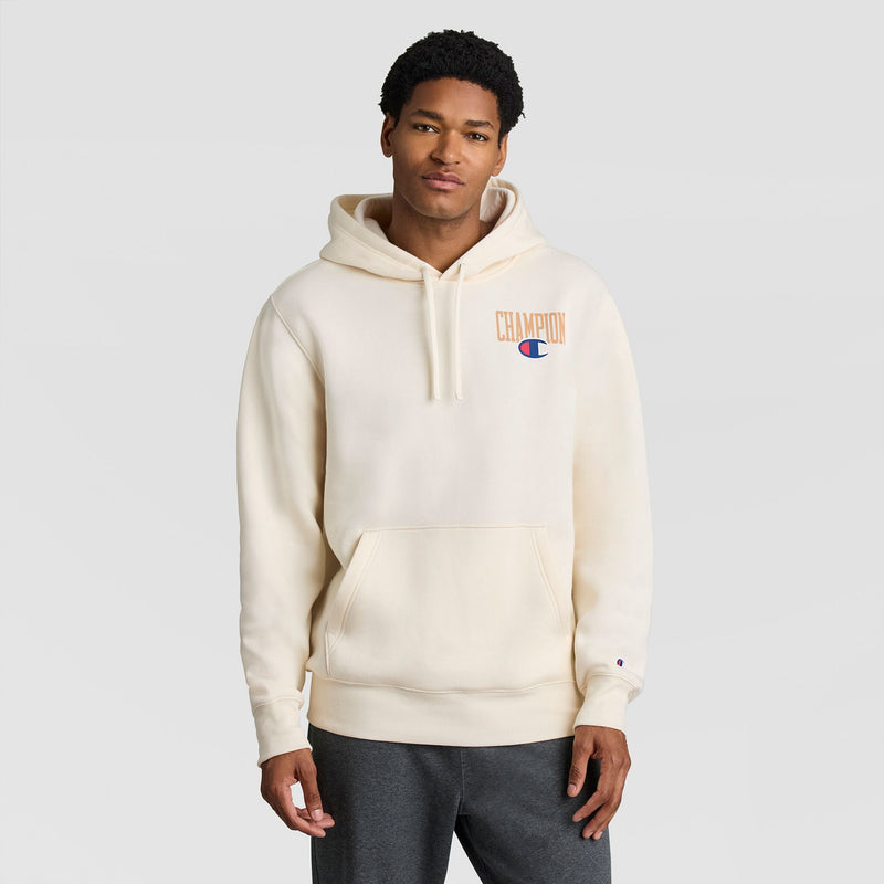A person wearing a cream-colored Fleece Hoodie, Left Chest Graphic by Champion, featuring a logo on the left chest.