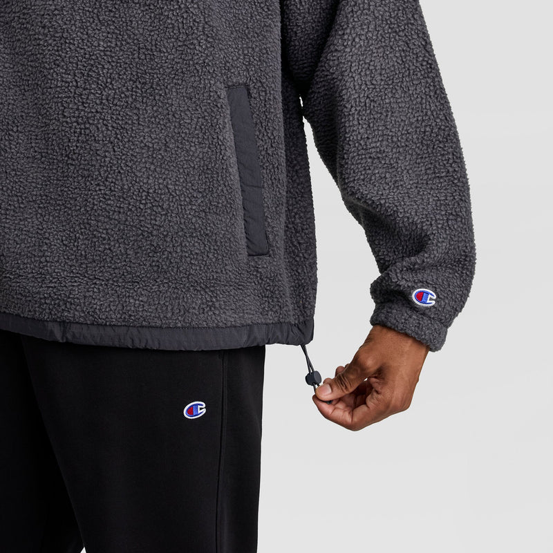 Close-up of a person adjusting the drawstring hem on a dark grey, textured Champion Polar Fleece Quarter Zip pullover.