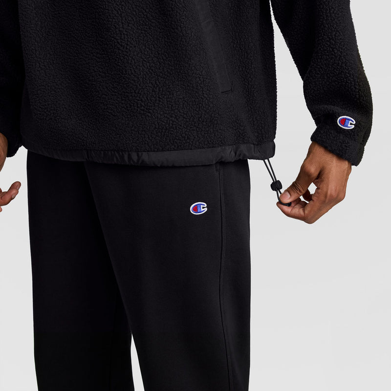 A person wearing a black textured Champion Polar Fleece Quarter Zip with a toggle hem and matching sweatpants.