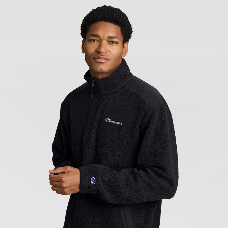 A man wearing a black textured Champion Polar Fleece Quarter Zip with a high collar and a logo on the chest and sleeve.