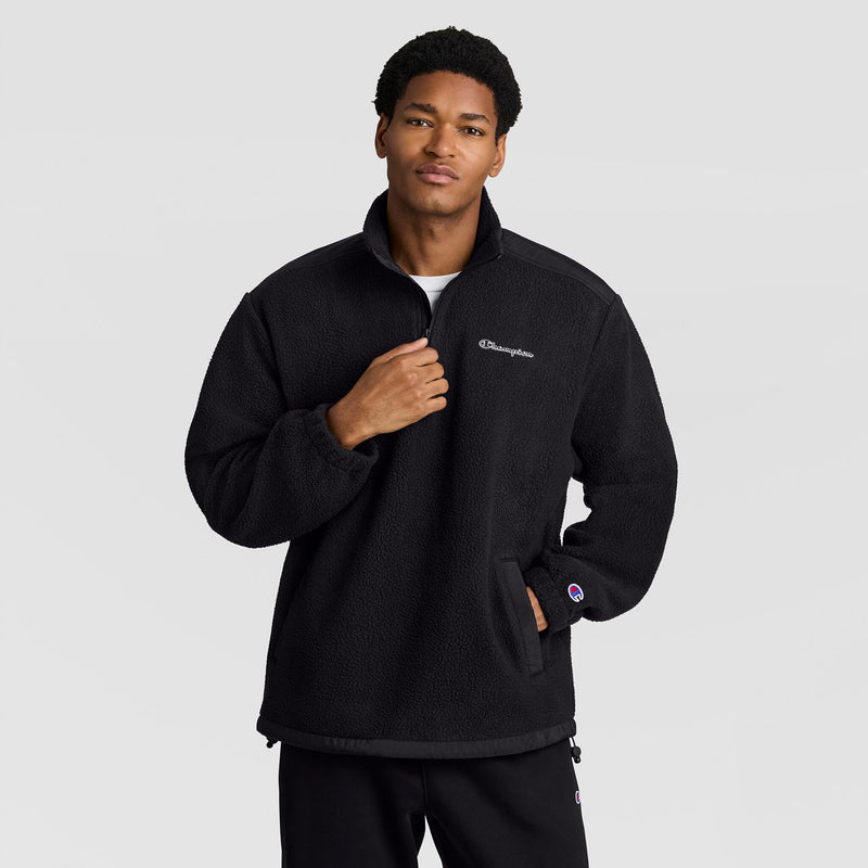 A person wears a black textured Champion Polar Fleece Quarter Zip quarter-zip pullover with a high collar and a small logo on the chest and left sleeve.