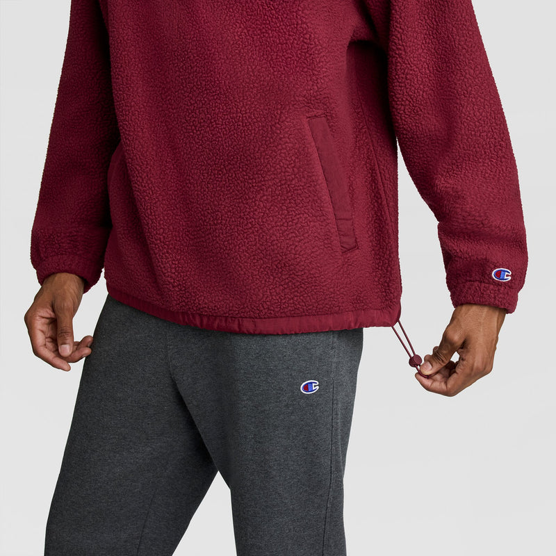 A person wearing a maroon Champion Polar Fleece Quarter Zip with a textured finish and toggle hem, paired with dark grey sweatpants.