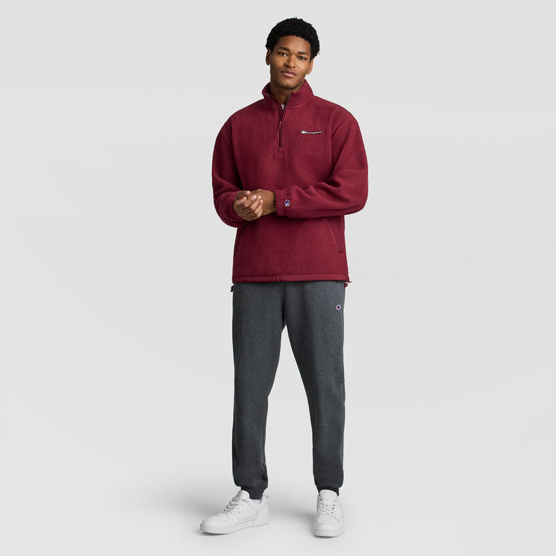 A man wearing a burgundy Polar Fleece Quarter Zip, dark gray sweatpants, and white sneakers.