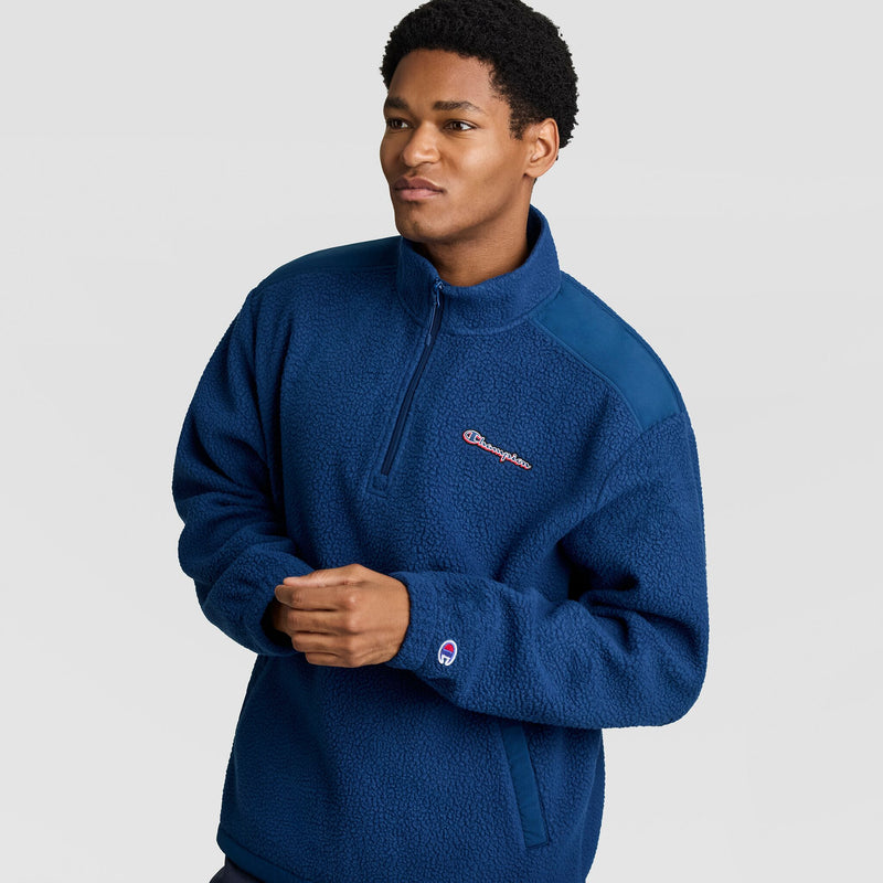 A man wearing a blue, textured Champion Polar Fleece Quarter Zip with a high collar and a logo on the chest.