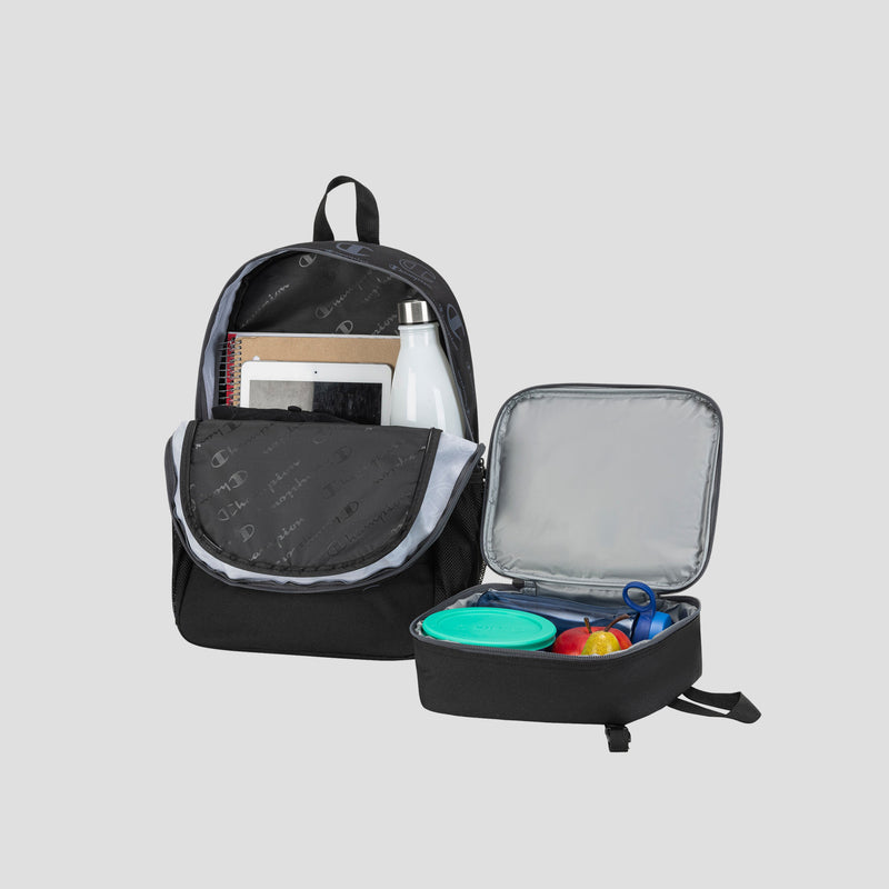 A black Champion Kids’ Mode Lunch Kit & Backpack Combo, featuring a youth backpack with notebooks and a white bottle inside, is placed next to an open insulated lunch box containing a green container, an apple, and a blue item. All items are set against a plain light gray background.