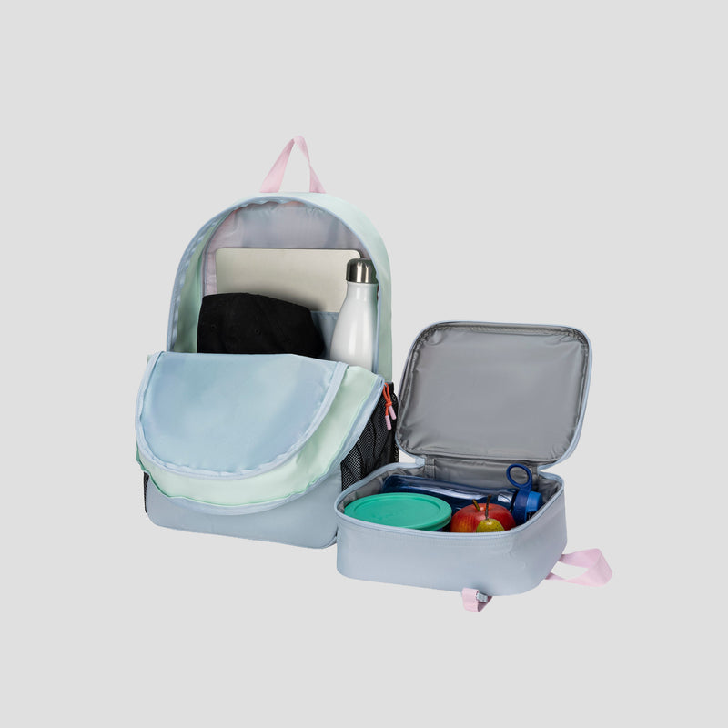 A pastel Champion Kids’ Mode Lunch Kit & Backpack Combo is displayed on a light gray background, featuring the backpack with an open front pocket revealing a notebook and black cloth, accompanied by a water bottle and an insulated lunch box filled with fruits and containers.