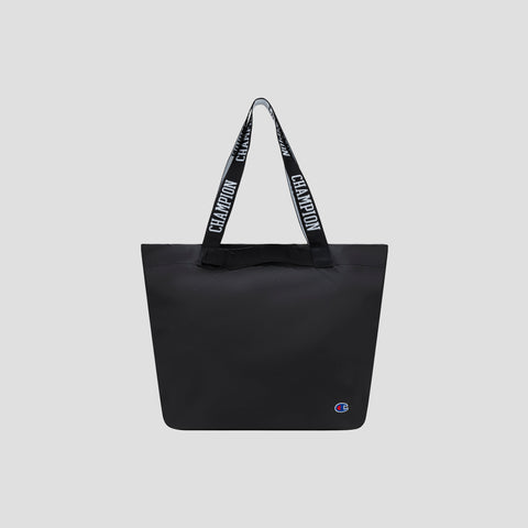 Miller Coated Shopper Tote by Champion in black, featuring “CHAMPION” text on the handles and a small Champion logo at the bottom right corner, displayed on a plain light gray background. This spacious shopper tote includes organizational pockets, making it ideal for keeping your essentials neatly arranged.