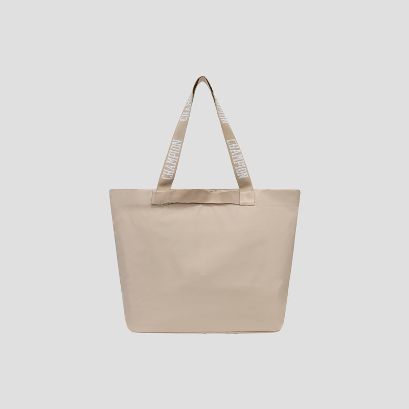 The Champion Miller Coated Shopper Tote is a spacious beige tote bag with two long handles, each featuring CHAMPION repeatedly printed in white capital letters on a beige background. With its simple, minimalist design and organizational pockets, this tote is perfect for keeping your essentials neatly arranged.