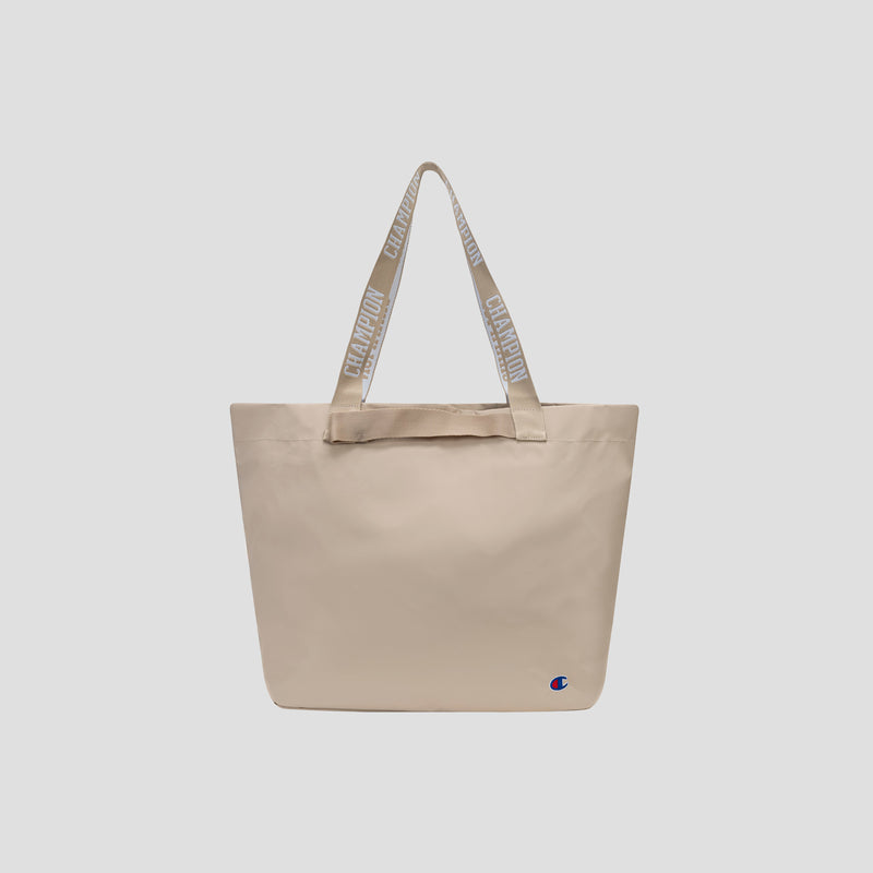 The Miller Coated Shopper Tote by Champion is a spacious beige bag featuring Champion-branded handles and a small Champion logo near the bottom right corner. Designed for organization, this tote offers multiple pockets to keep your essentials in order and is shown against a plain light background.