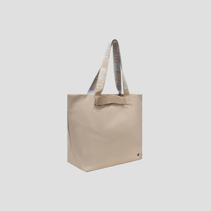 The Champion Miller Coated Shopper Tote is a spacious beige bag with two handles and features the word “CHAMPION” in large letters. It has a simple, minimalist design, includes a small Champion logo near the bottom corner, and comes with organizational pockets to keep your essentials neatly arranged.