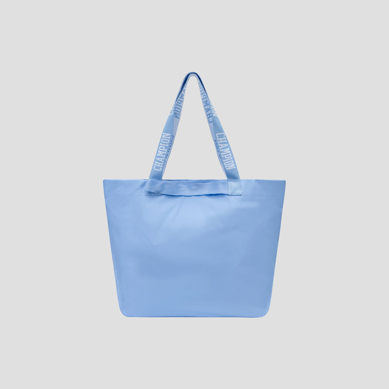 Light blue Champion Miller Coated Shopper Tote with two wide handles and repeating white CHAMPION text, displayed against a plain light gray background. This weather-resistant, spacious tote is perfect for carrying your essentials in style.