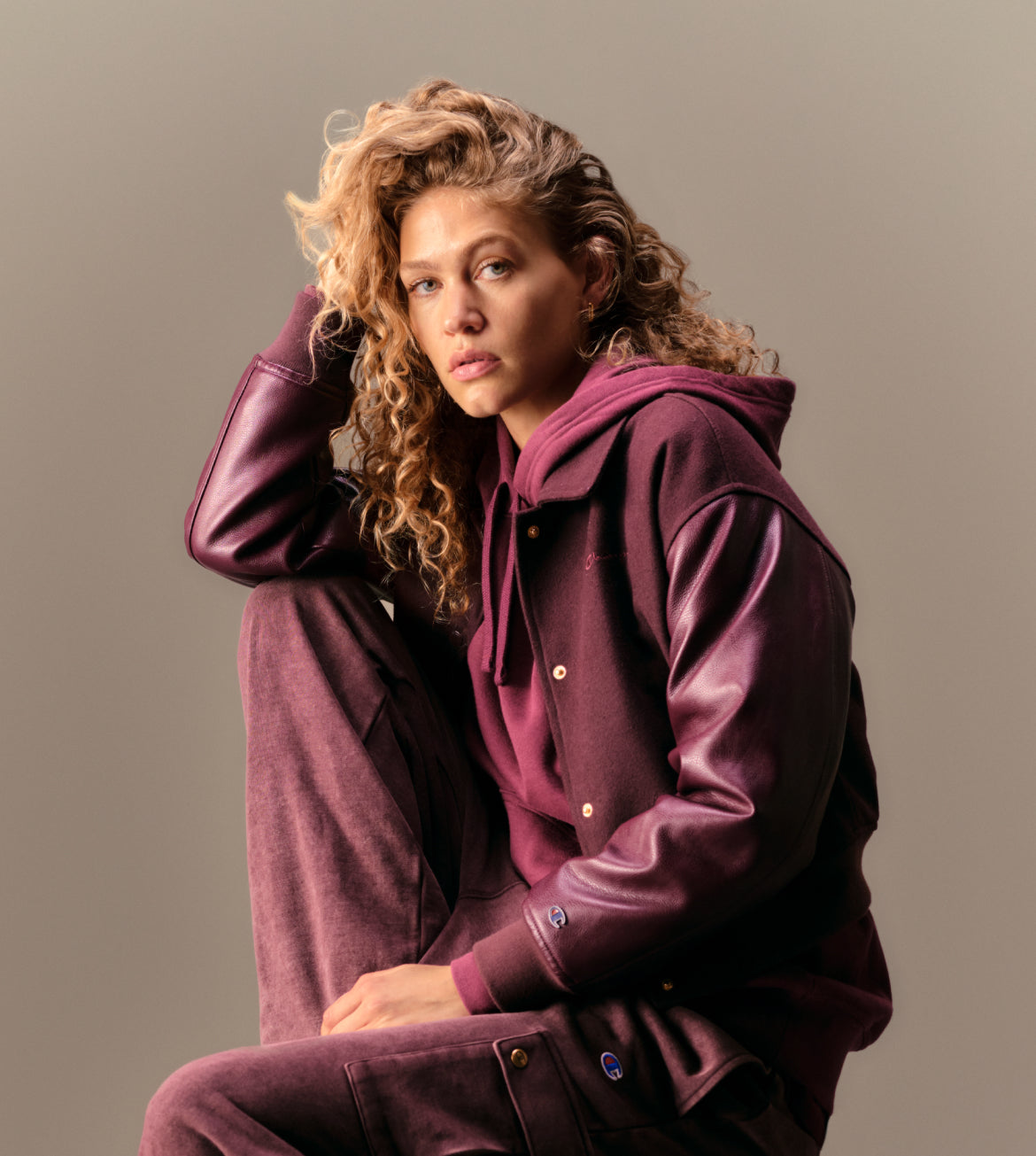 Person wearing a maroon outfit sitting against a plain background