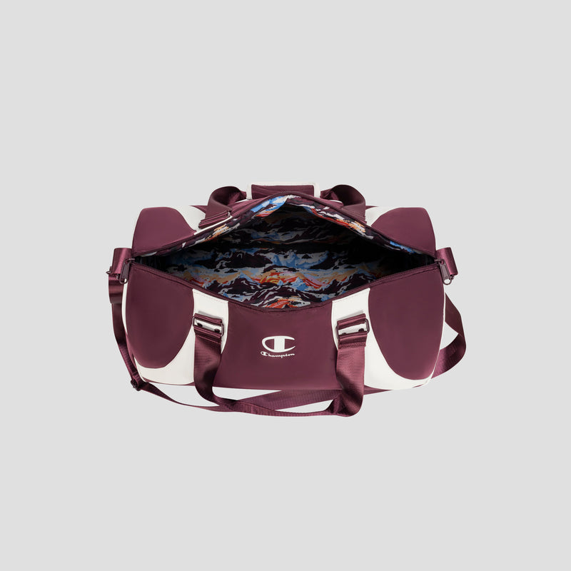 A maroon and white Oracle Duffel Bag by Champion, featuring handles and a shoulder strap, sits open to reveal its colorful, patterned interior lining. The stylish sports bag displays the Champion logo on the front pocket.