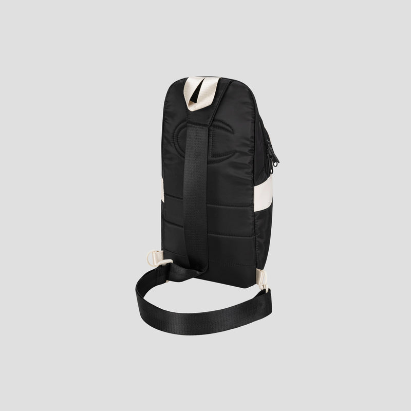 A black Champion Oracle Sling Pack crossbody bag with a wide adjustable shoulder strap and white accent detail, shown from the back against a plain light gray background.