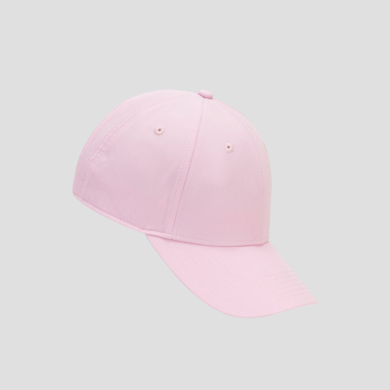 A light pink Champion Ponytail Baseball Cap, crafted from performance stretch fabric, is displayed on a plain gray background, angled to the left with its curved brim in view. This stylish cap features a ponytail-accommodating design for optimal comfort and functionality.