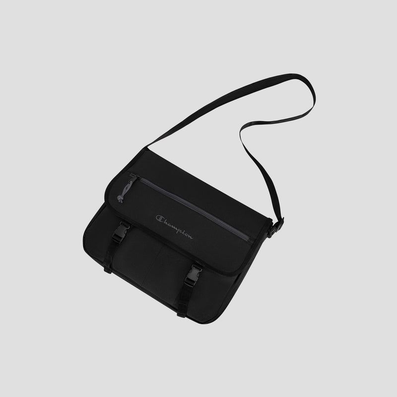The Champion Phase Messenger Bag, shown against a light gray background, is a black messenger bag with a built-in laptop sleeve, shoulder strap, front zipper pocket, two buckle closures, and the Champion logo on the flap.
