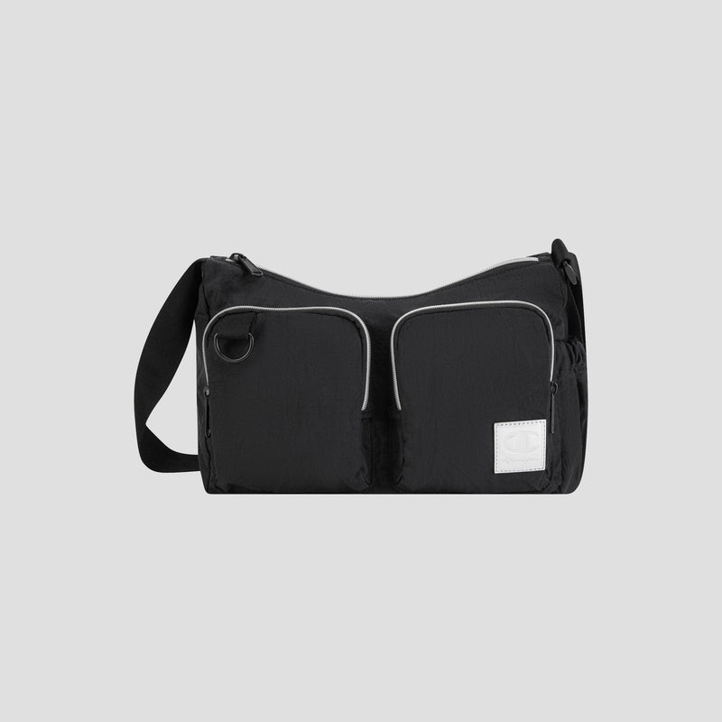 The Champion Quartz Small Messenger Bag, crafted from lightweight black nylon, features two front zippered pockets, a white rectangular patch, and an adjustable strap. It is photographed against a plain light gray background.