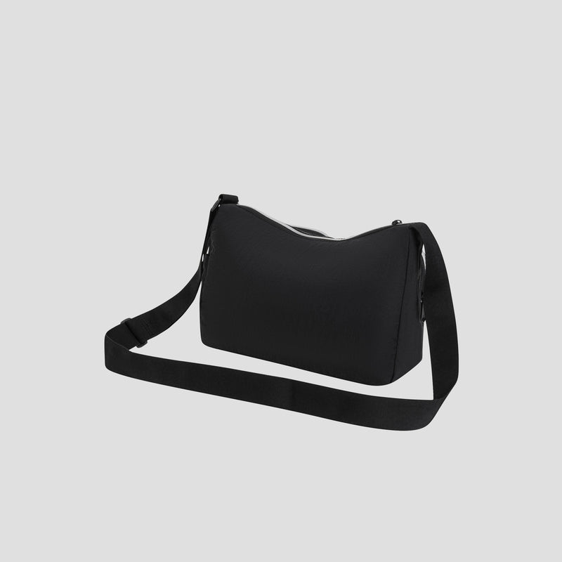 The Champion Quartz Small Messenger Bag is a plain black, lightweight nylon bag featuring a long adjustable strap. Displayed against a light gray background, this bag has a simple rectangular shape and a top zipper closure, making it an ideal travel companion for carrying daily essentials.