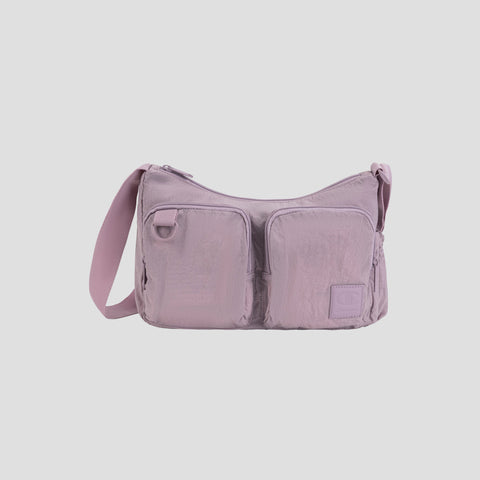 The Champion Quartz Small Messenger Bag, shown here in light purple and crafted from lightweight nylon, features two front zippered pockets, a long adjustable strap, and a small rectangular patch on the lower right side—perfect for carrying daily essentials while traveling, all displayed against a plain white background.