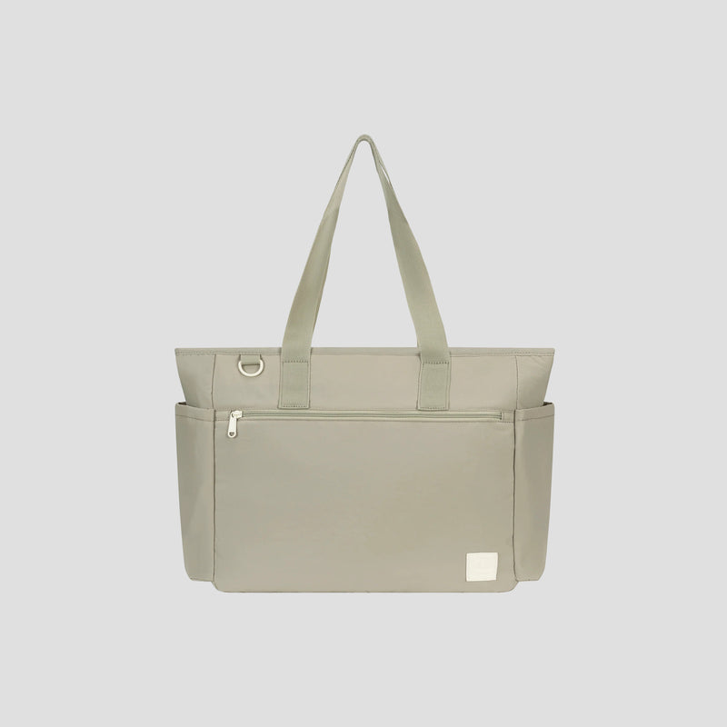 Introducing the Champion Quartz East West Tote—a lightweight crinkle nylon bag in light gray. This stylish travel tote features two handles, a front zipper pocket, two side pockets, and a small white patch on the bottom right. Designed for convenience, it includes a padded laptop sleeve and a silver ring detail near the handle, all presented against a plain gray background.