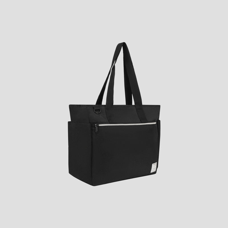 The Champion Quartz East West Tote is a black crinkle nylon bag with long handles, featuring a front zippered pocket and a small white label on the lower right corner. Shown against a light gray background, this stylish tote is designed for travel with a padded laptop sleeve that keeps your essentials protected and organized on the go.