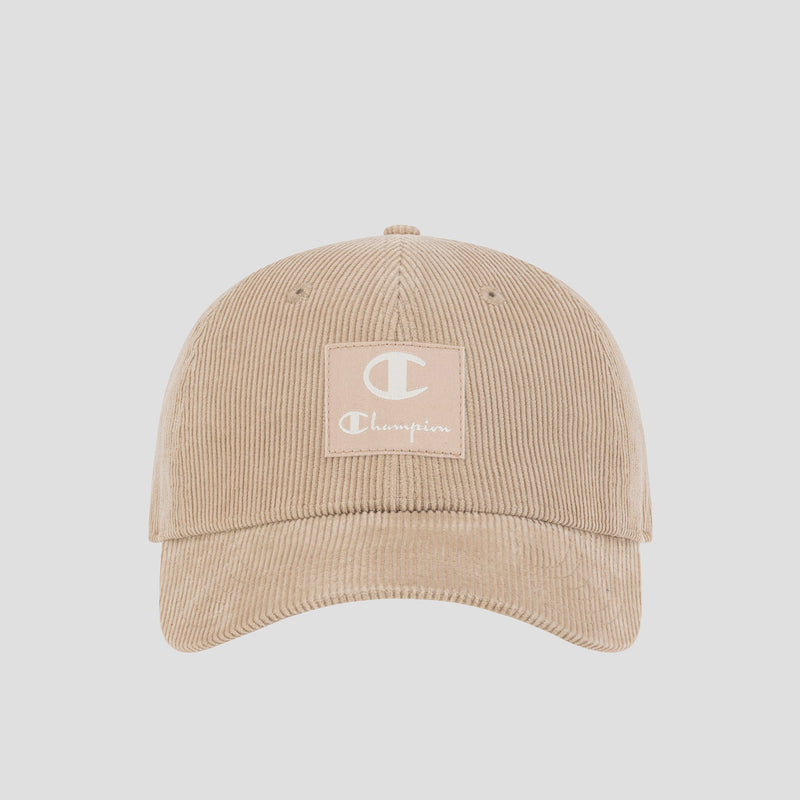 The Ridge Corduroy Adjustable Cap by Champion is a beige corduroy hat featuring a square patch on the front with a white “C” and the word “Champion” in white text, complete with an adjustable back closure for a comfortable fit and vintage-inspired style.