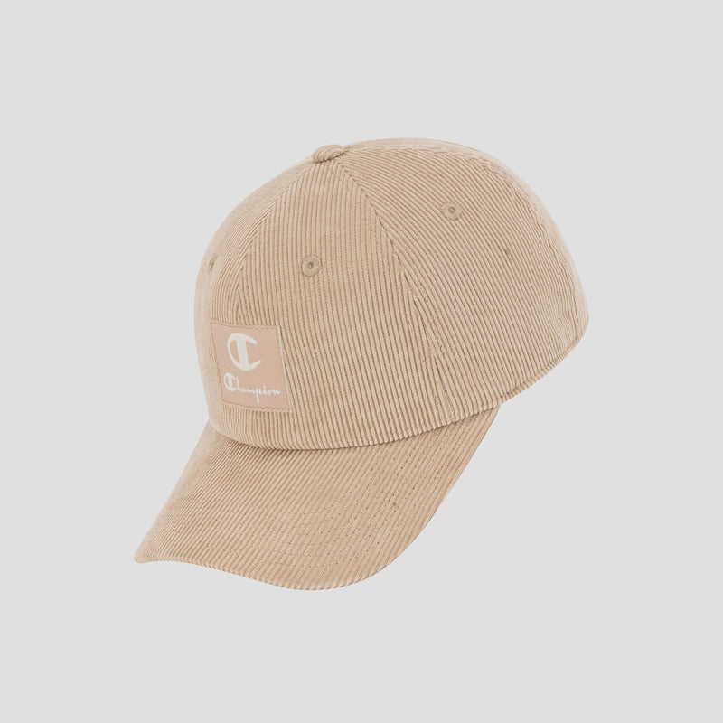 The Ridge Corduroy Adjustable Cap by Champion features a beige corduroy design with a curved brim and a front patch displaying the Champion logo, delivering vintage-inspired style. Presented against a plain white background, this cap includes an adjustable back closure for a comfortable fit.