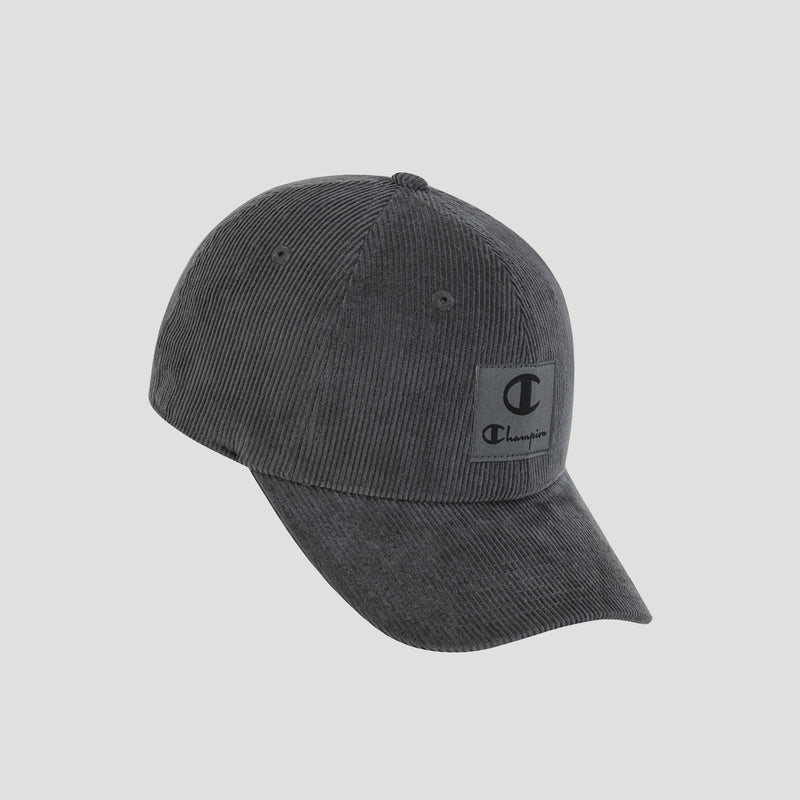 Introducing the Ridge Corduroy Adjustable Cap by Champion—a dark gray vintage-style baseball cap crafted from corduroy, featuring a curved brim and a rectangular front patch with the iconic Champion logo and text. Designed for everyday comfort, this cap offers a relaxed fit with its adjustable back closure, perfectly blending classic style and ease.