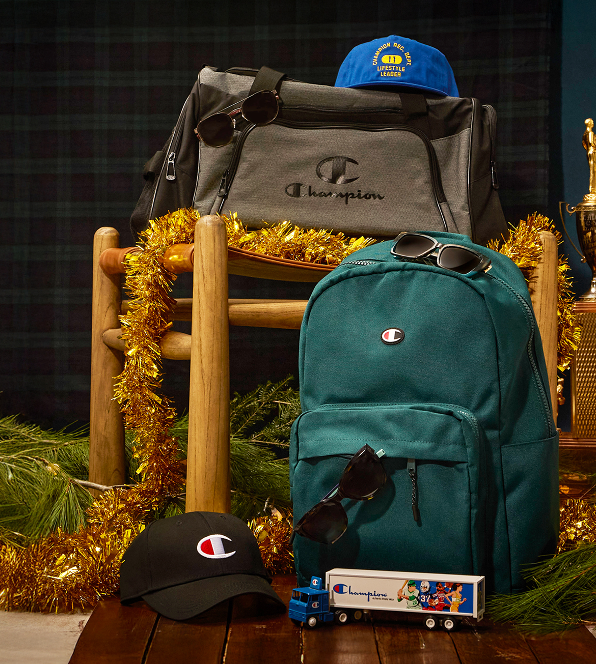 Champion branded items including a backpack, cap, sunglasses, and toys on a wooden chair with decorative elements.
