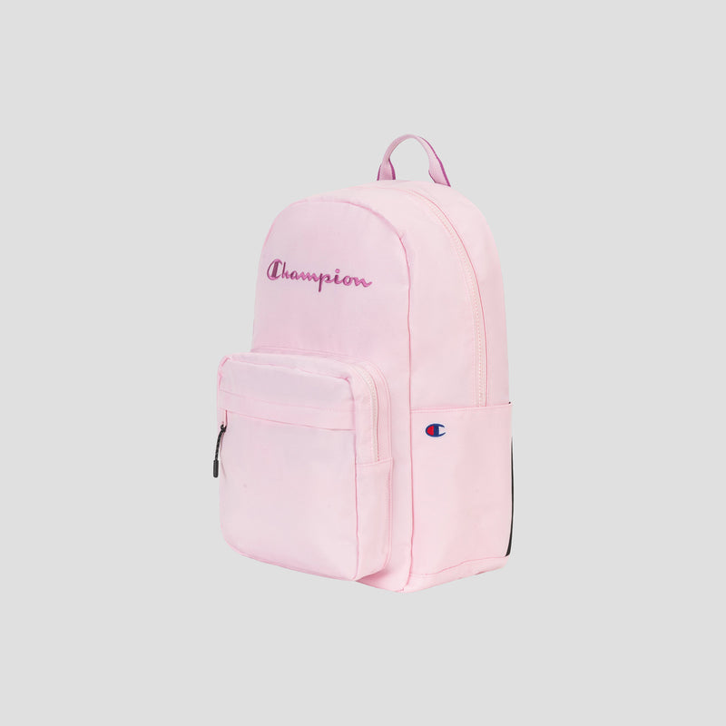 The Steady Backpack by Champion in light pink features a front zip pocket, side pocket, top handle, and a purple embroidered Champion logo on the front. Designed for practicality, it also includes a padded laptop sleeve for extra protection. The background is plain light gray.