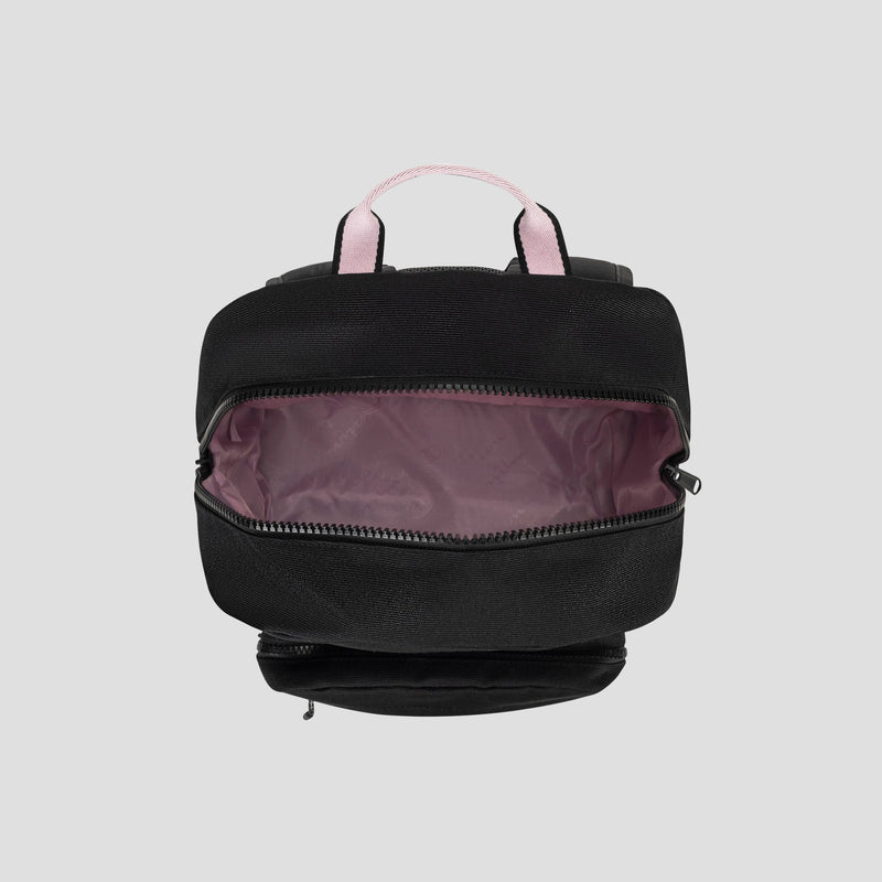 The Champion Steady Backpack is displayed from above in black with light pink handles. Its main zipper compartment is open to show a light mauve-pink interior lining and a padded laptop sleeve for organizing daily essentials. The background is plain light gray.