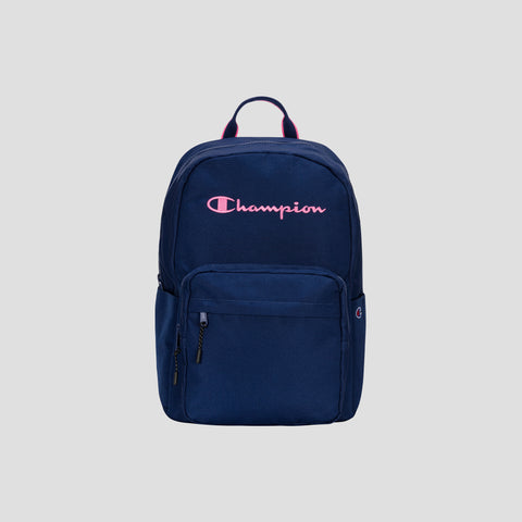 A Champion Steady Backpack in navy blue featuring a front zip pocket and a pink Champion logo on the upper front, shown against a plain gray background. Ideal for daily use or as a laptop backpack for travel.