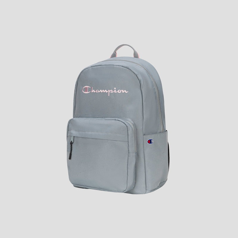 The Steady Backpack by Champion is shown upright against a plain, light background. This light gray backpack features a front zip pocket, a top handle, and the embroidered Champion logo on the front.