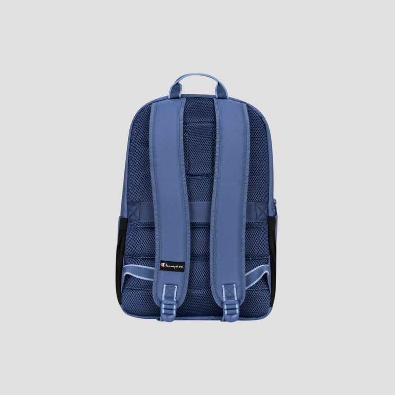 The Steady Backpack by Champion is displayed from the back against a light gray background, highlighting its two padded shoulder straps, top handle, mesh padding, and black side pockets. This blue backpack is designed for everyday versatility and comfortably fits up to a 17″ laptop.
