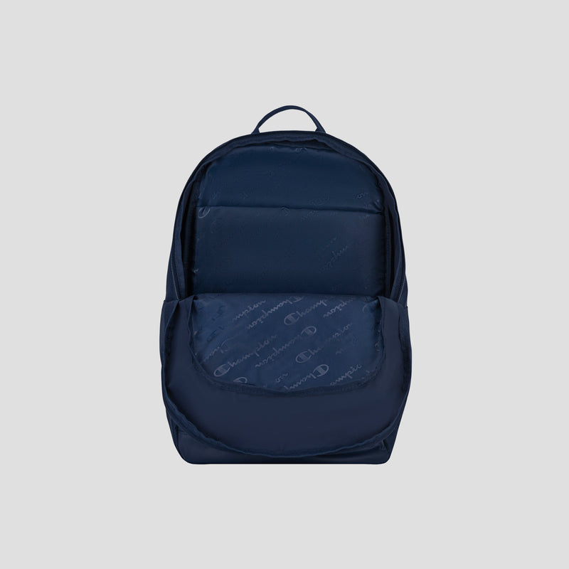 The Champion System Backpack, shown in navy blue against a light gray background, features a front pocket slightly open to reveal its patterned interior and multiple storage compartments.