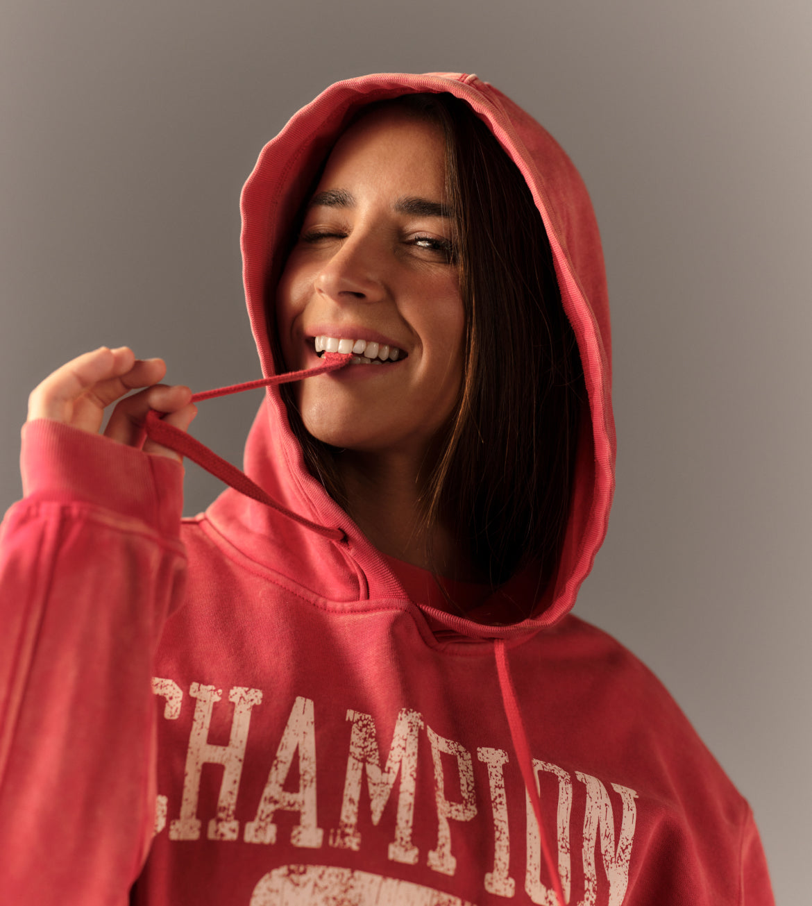Person wearing a red 'Champion' hoodie against a gray background