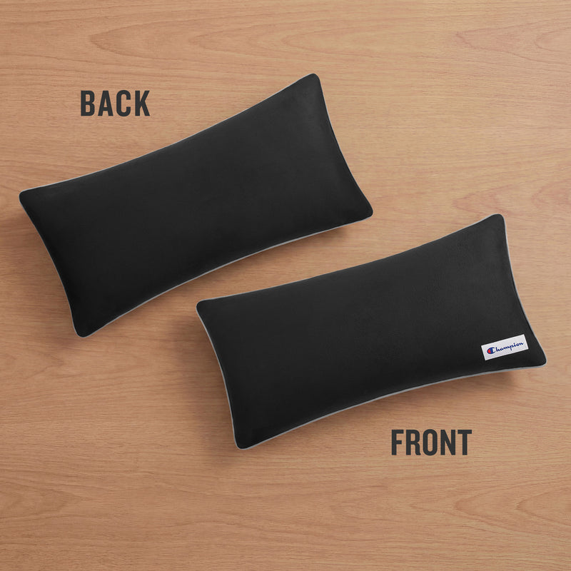 Two rectangular black Faux Wool Body Pillows by Champion with plush polyester fill rest on a wooden surface; one labeled BACK is unbranded, while the other labeled FRONT displays a small Champion logo tag on the bottom right corner.