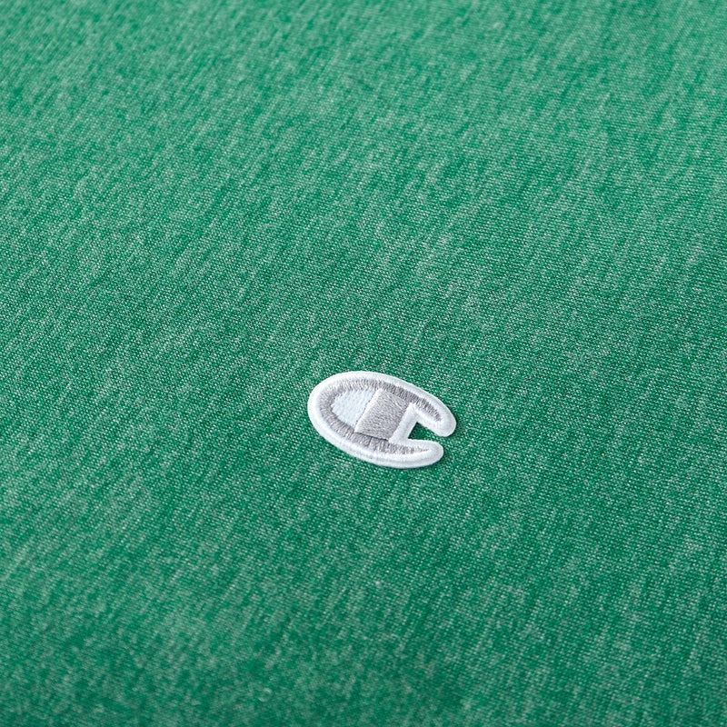 A close-up of a small, white and gray embroidered Champion C logo on green fabric—reminiscent of the signature detailing found on Champion’s Reversible Solid Jersey Comforter Sets.