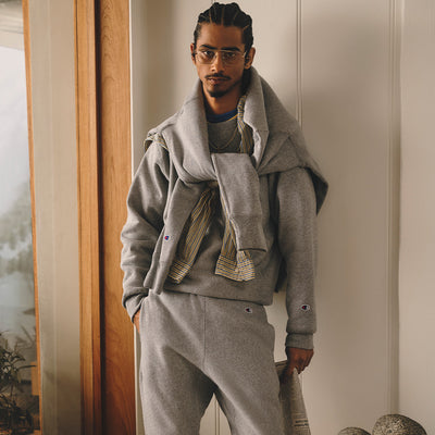 Man wearing a gray outfit standing indoors with a neutral background