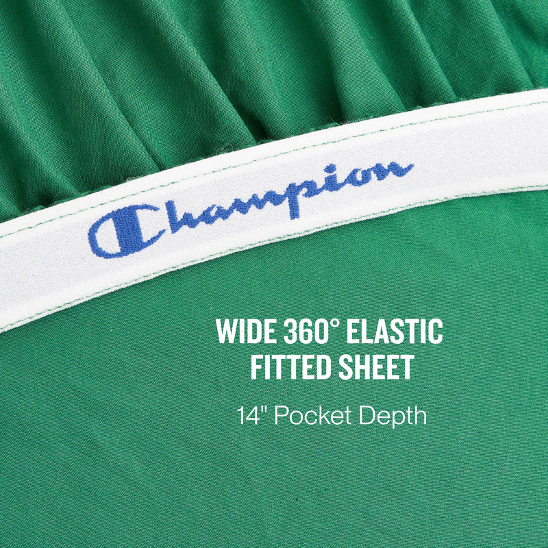 Close-up of a green fitted sheet with a white elastic band featuring the blue Champion logo. Text overlays read: WIDE 360° ELASTIC FITTED SHEET and 14″ Pocket Depth. Experience athletic bedding at its finest with the Peak Comfort Microfiber Sheet Set from Champion, crafted for a secure and comfortable fit with deep pockets.