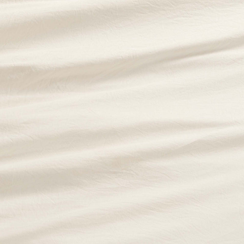 Close-up of the Champion Elastic Logo Microfiber Sheet Set in an off-white shade, showcasing gentle creases and a subtle textured surface. The lighting brings out the soft folds, highlighting the inviting and cozy feel of this everyday bedding essential.