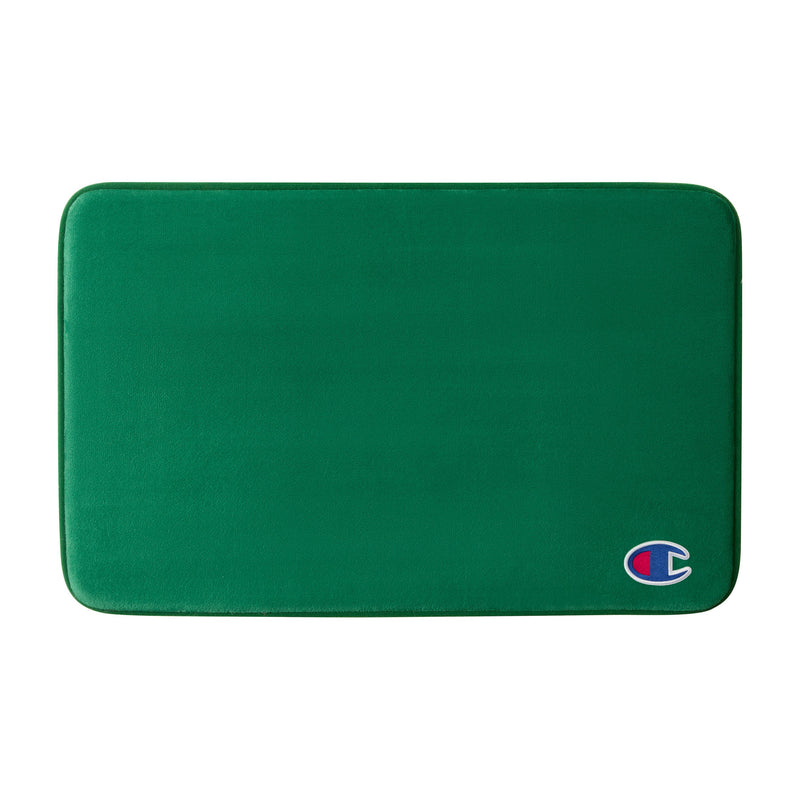 A green rectangular Logo Patch Memory Foam Bath Mat by Champion, featuring rounded corners and a small Champion logo patch on the bottom right, designed with plush memory foam for enhanced comfort and a skid-resistant backing to keep it securely in place.